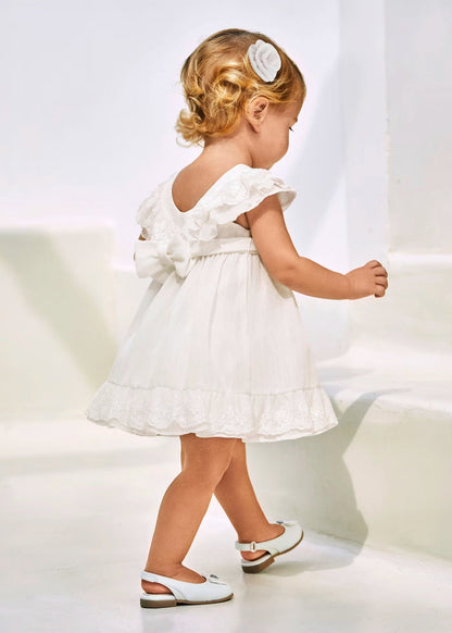 vestido ceremonia con fajin, y olan en la falda color blanco y flor rosa