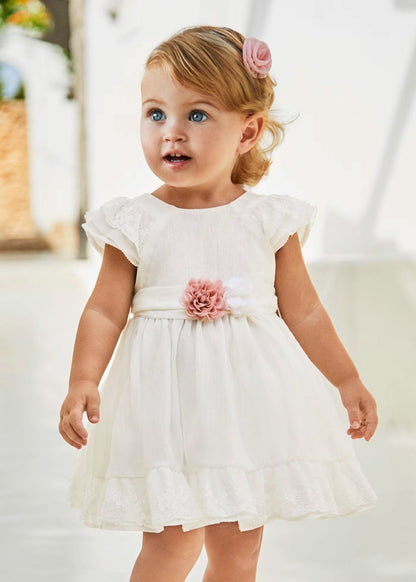 vestido ceremonia con fajin, y olan en la falda color blanco y flor rosa